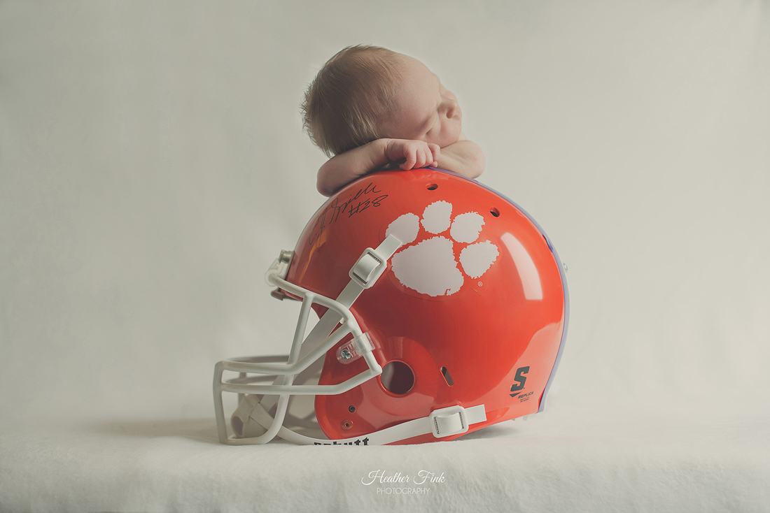 newborn baby boy laying on clemson helmet signed by AJ Spiller