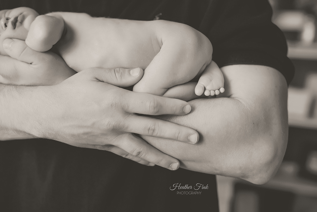 newborn baby's tiny toes against daddy's arms
