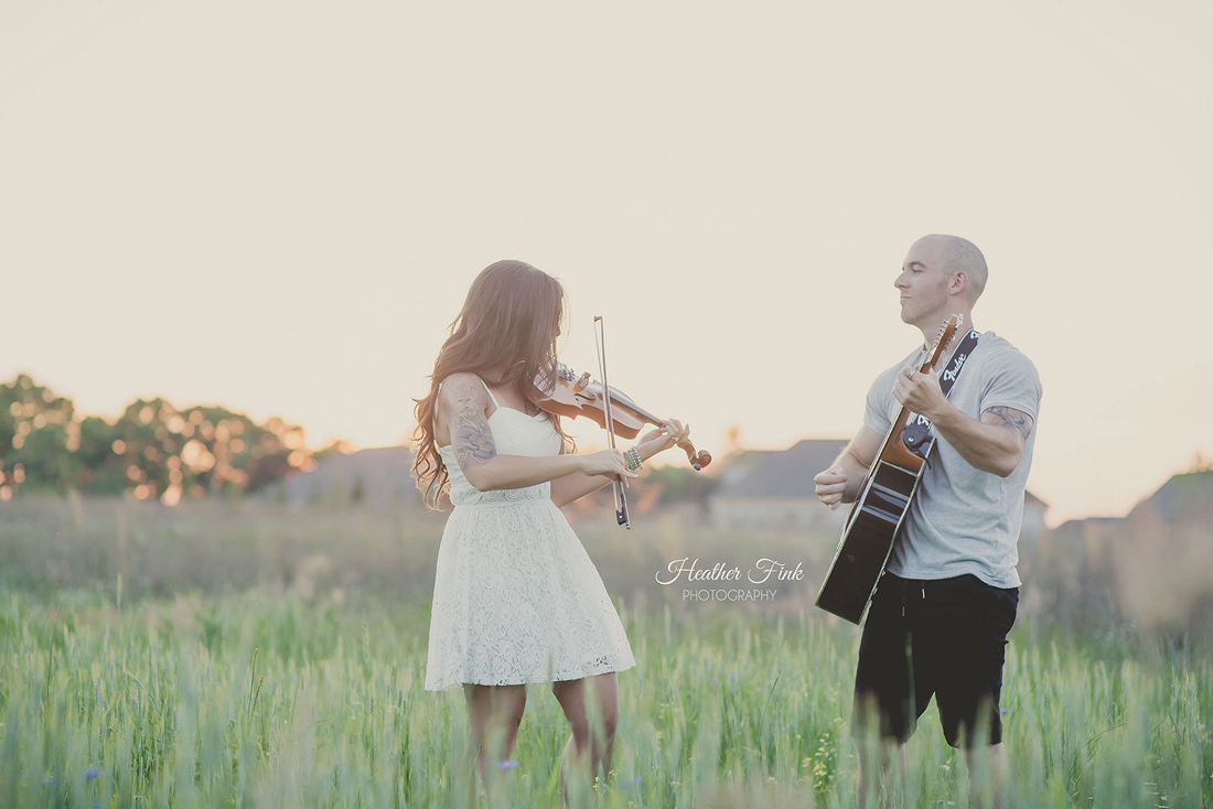 couple playing a violin and guitar in a field