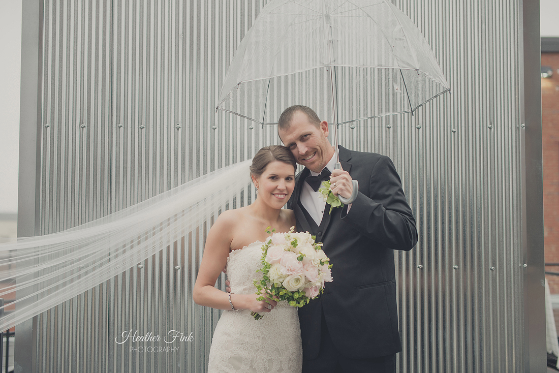 bride and groom standing in the rain