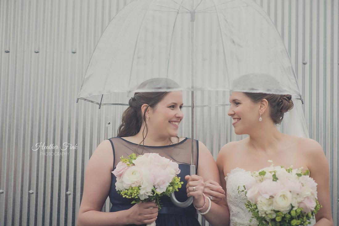 bride and her sister under clear umbrella