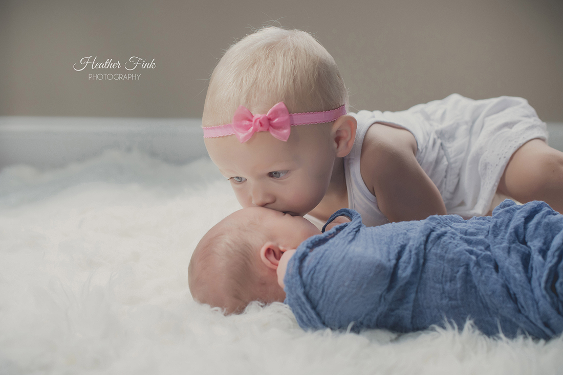big sister kisses her new baby brother
